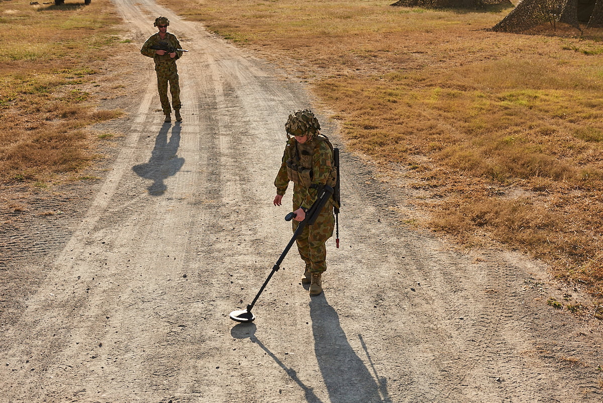 An Army member outside with a metal detector.