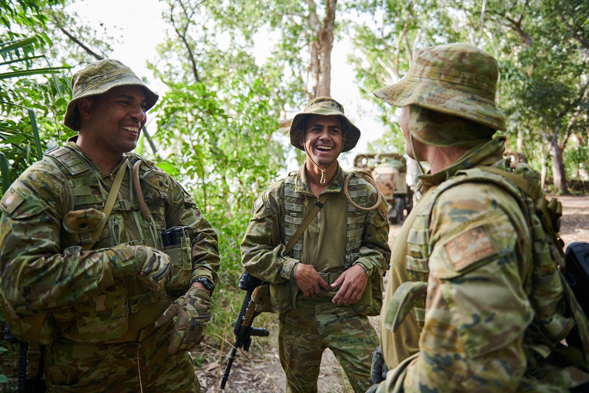 An Indigenous man in Army uniform share a laugh with his mates.
