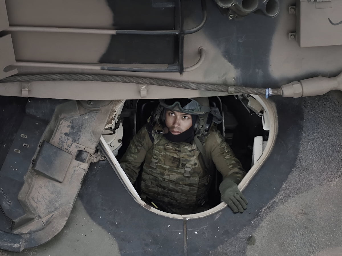 A man in the Army looking up from inside a tank.