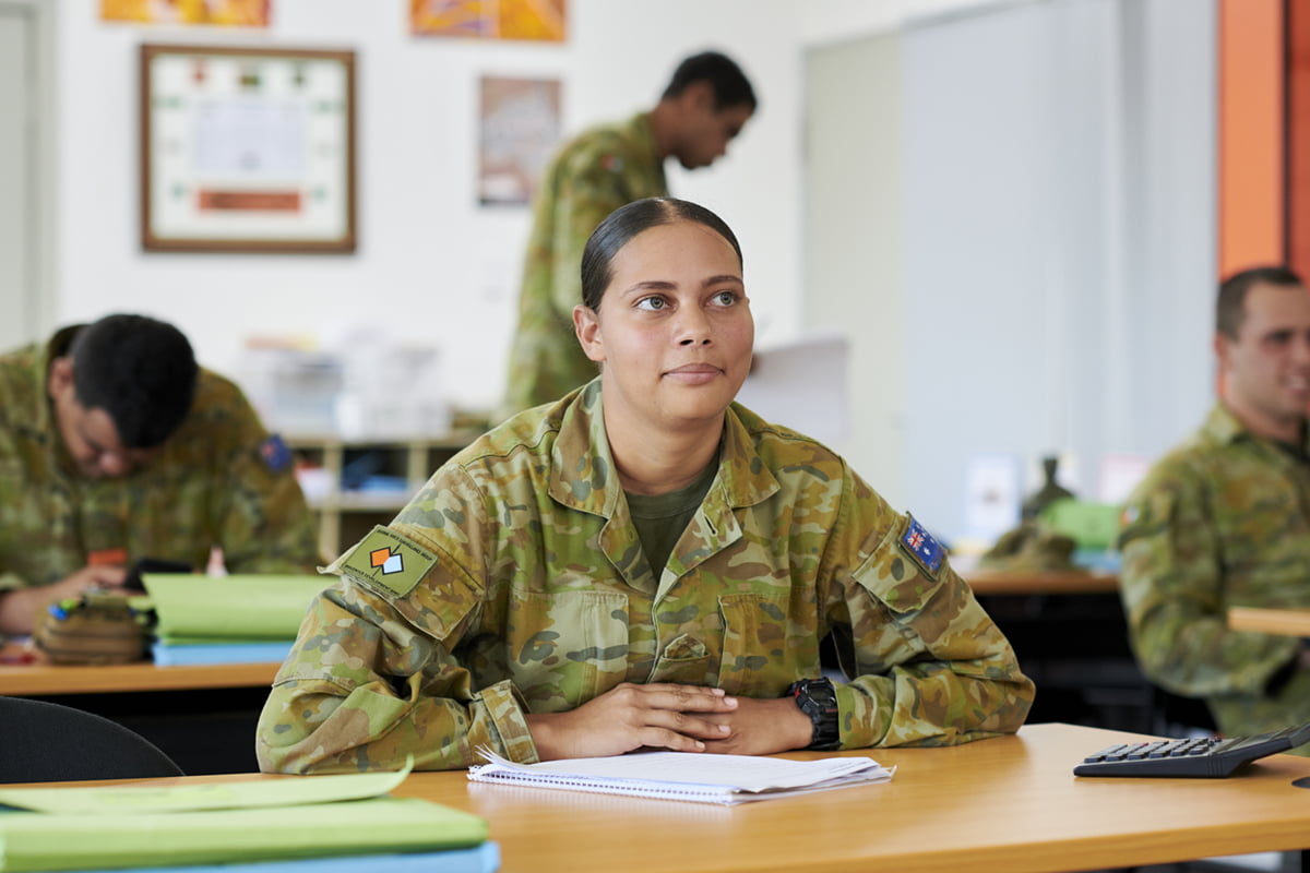 A women in uniform sits at a desk.