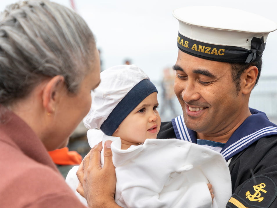 A member of the Navy looking happily at his small child.
