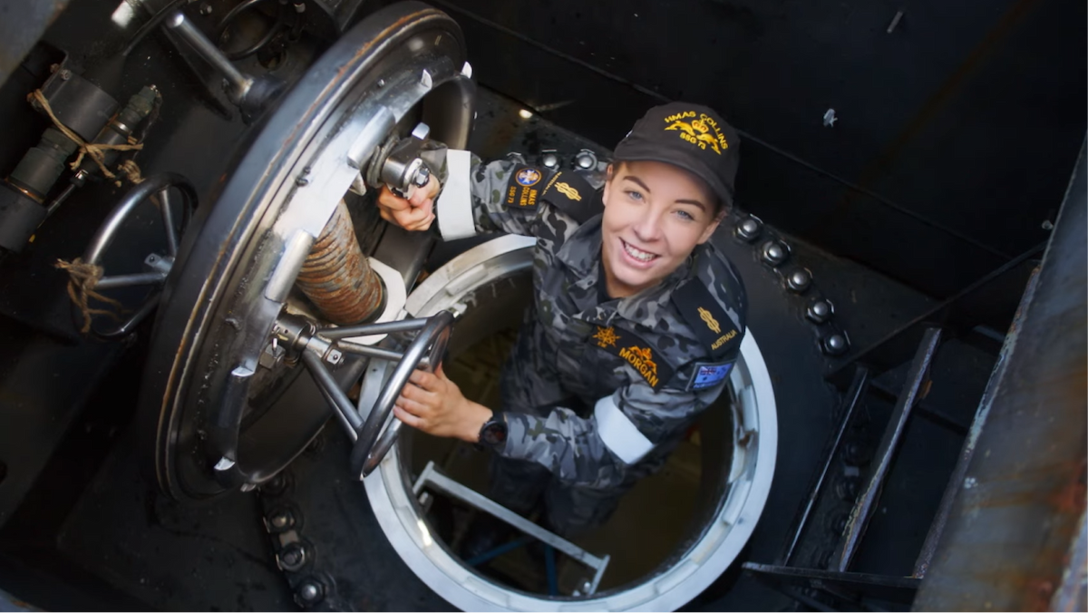 A woman in the Navy in a submarine looking up.
